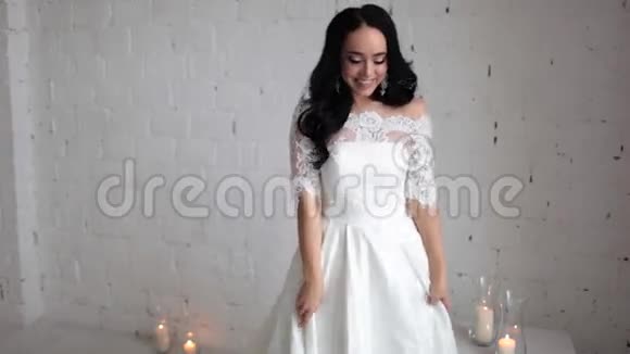 穿着白色婚纱的美丽黑发新娘坐在椅子上手里拿着棉花树枝视频的预览图