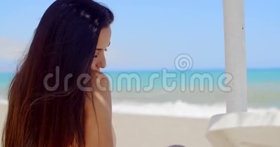 海滩上迷人的女士在镜头前微笑视频的预览图