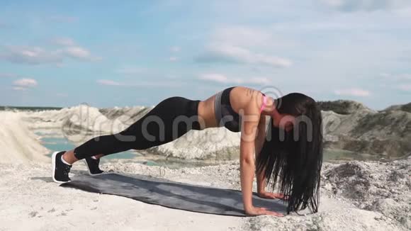 穿着黑色运动服的运动型黑发女孩在一个蓝水白垩沙场上训练表演视频的预览图