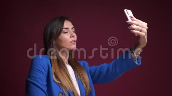 有魅力的白种人女性在手机上自拍并在镜头前微笑的特写镜头视频的预览图
