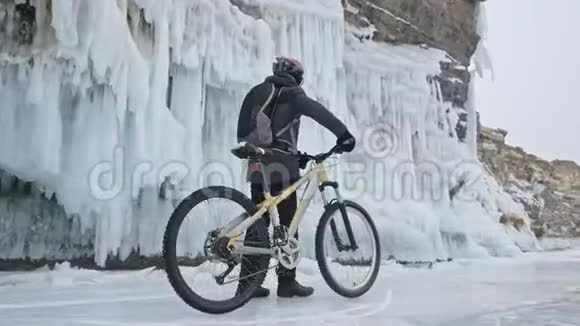人在冰窟附近的自行车旁散步有冰洞和冰柱的岩石非常美丽骑自行车的是视频的预览图