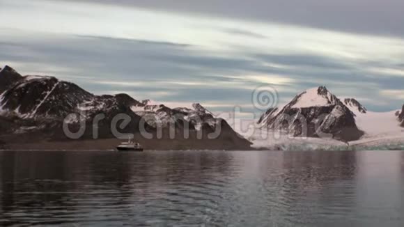 斯瓦尔巴雪山背景下北冰洋水中的船舶视频的预览图