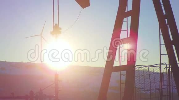 阳光洒在油井上背景是抽油机和风力发电厂视频的预览图