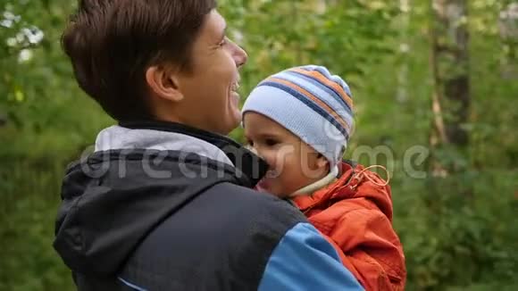 一个年轻的父亲把他的孩子抱在怀里温柔和怀抱的挚爱父亲户外活动视频的预览图