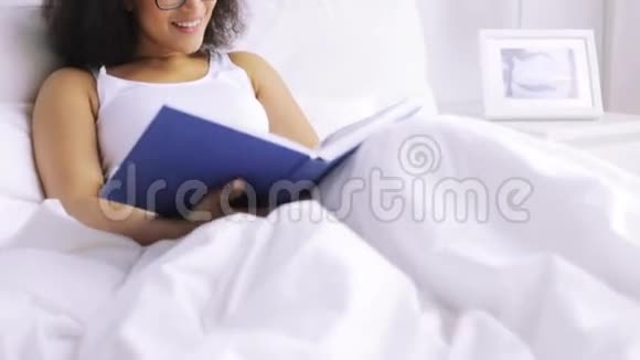 非洲妇女在家卧室的床上看书视频的预览图