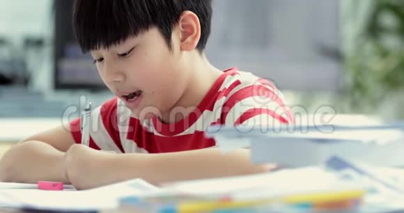 认真的亚洲男孩在家做作业视频的预览图