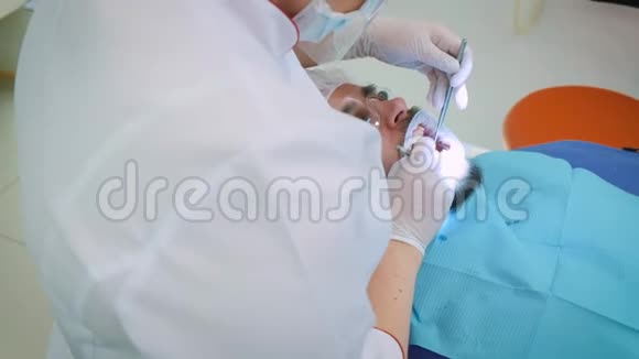 在办公室工作的牙医女医生检查男性病人的牙齿和下巴视频的预览图
