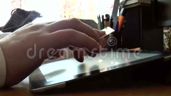 男性使用平板电脑和信用卡特写视频的预览图