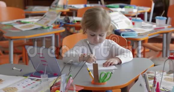 女孩在教室的桌子上画画教育坐在书桌前的孩子视频的预览图