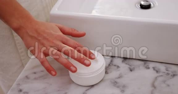 女人在浴室的脸上涂抹保湿霜视频的预览图