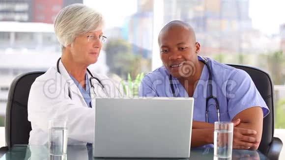 微笑的医生在笔记本电脑前和护士说话视频的预览图