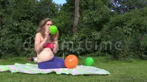 可爱的孕妇女孩在花园里充气五颜六色的气球视频的预览图