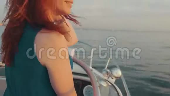 红发女孩穿着绿松石服装驾驶摩托艇美丽的日落晚上好视频的预览图