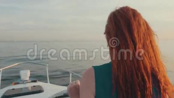 红发女孩穿着绿松石服装驾驶摩托艇美丽的日落很浪漫视频的预览图