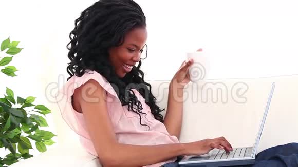 微笑的女人在笔记本电脑前喝咖啡视频的预览图