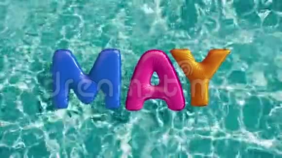 单词5月形状的充气游泳圈漂浮在清爽的蓝色游泳池视频的预览图