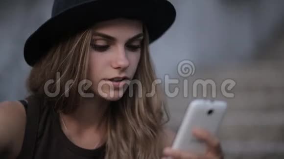戴着黑帽子的漂亮女孩正在智能手机上输入一条信息视频的预览图