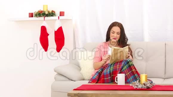 圣诞节时漂亮的黑发女人在沙发上放松视频的预览图
