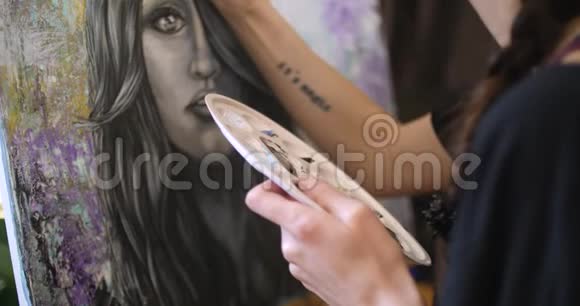 女艺术家画了一幅萨满画艺术家在她的车间里用丙烯酸颜料描绘画布上的画面视频的预览图