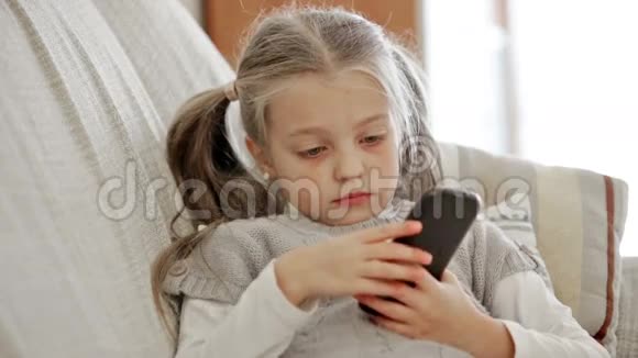 可爱的小女孩在家玩智能手机视频的预览图