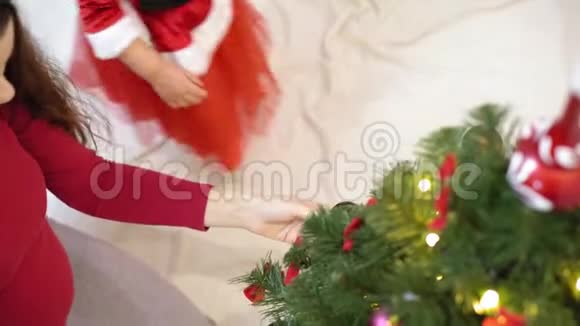 宝宝和孕妈在圣诞树上挂红球玩具快乐的童年概念孩子和母亲用视频的预览图