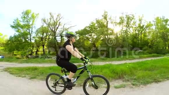 在绿色公园骑自行车的年轻女子视频的预览图