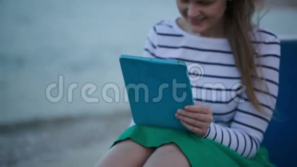 在海边使用平板电脑的年轻女性视频的预览图