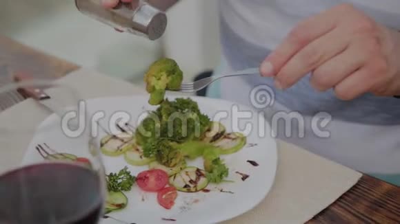 一个年轻人正在露天露台上的一家餐馆里用蔬菜沙拉吃午饭健康食品视频的预览图
