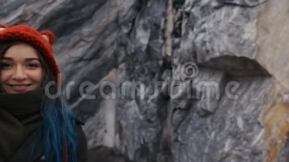 岩石悬崖背景上一个美丽的时髦女孩的肖像染发蓝色长视频的预览图