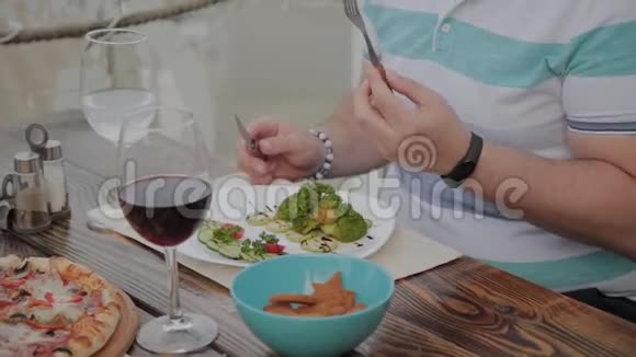 一个年轻人正在露天露台上的一家餐馆里用蔬菜沙拉吃午饭健康食品视频的预览图