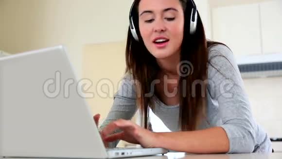 漂亮的黑发女人用笔记本电脑听音乐视频的预览图