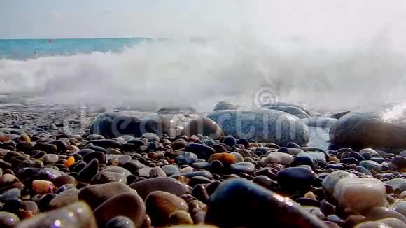 卵石海滩小卵石和海浪船在海上海的表面在一个野生鹅卵石海滩上波浪是视频的预览图