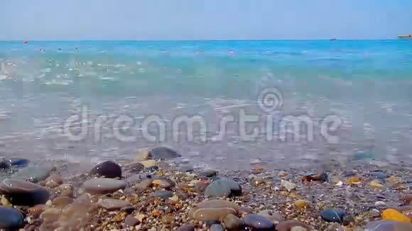 卵石海滩小卵石和海浪船在海上海的表面在一个野生鹅卵石海滩上波浪是视频的预览图