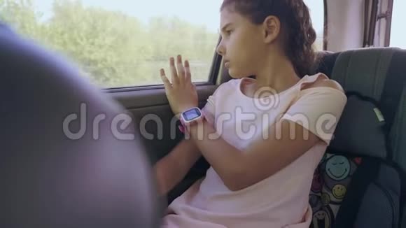 伤心的女孩无聊地坐在车里后座旅行运动小女孩在车里无聊概念长途旅行视频的预览图