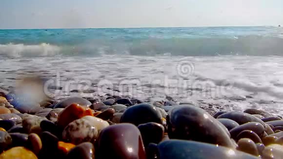 卵石海滩小卵石和海浪船在海上海的表面在一个野生鹅卵石海滩上波浪是视频的预览图