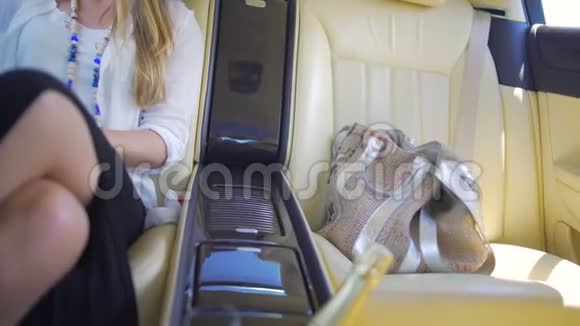 漂亮的富婆坐在豪华轿车的后座上享受度假视频的预览图