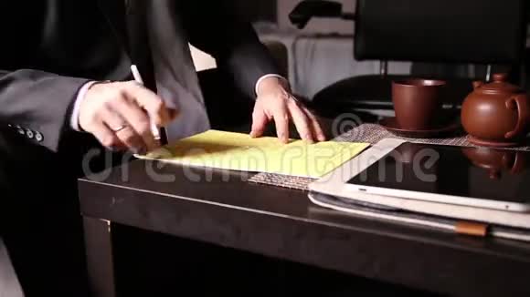 坐在办公桌前的商人签署了一份与个人电脑平板电脑比较的法案一个男人的特写和一个喷泉视频的预览图