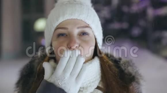一位年轻女子在广场上的冬夜圣诞树附近的肖像视频的预览图