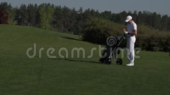 快乐的男人和他的儿子在夏日的完美高尔夫球场上行走视频的预览图