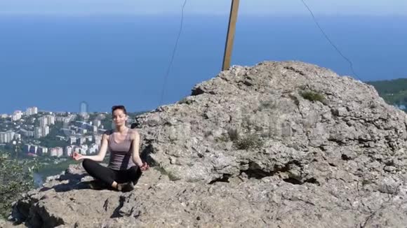 女旅行者在山上冥想坐在莲花的位置上的悬崖上视频的预览图