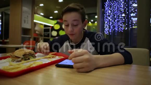 青少年吃法国薯条和使用智能手机视频的预览图