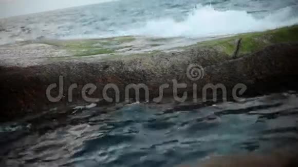 岩石海滩上的波浪和泡沫海洋中的防波堤视频的预览图