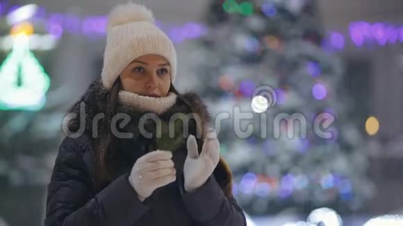 一位年轻女子在广场上的圣诞树旁的画像视频的预览图