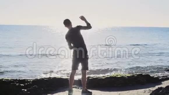 男跑运动员在沙滩上慢动作的阳光下热身视频的预览图