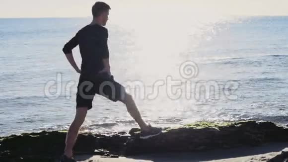 男跑运动员在沙滩上慢动作的阳光下热身视频的预览图