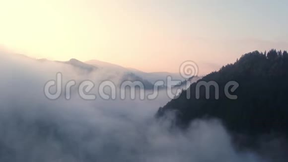 从山顶的云层中飞过高耸的山峰美妙的早晨日出自然景观视频的预览图