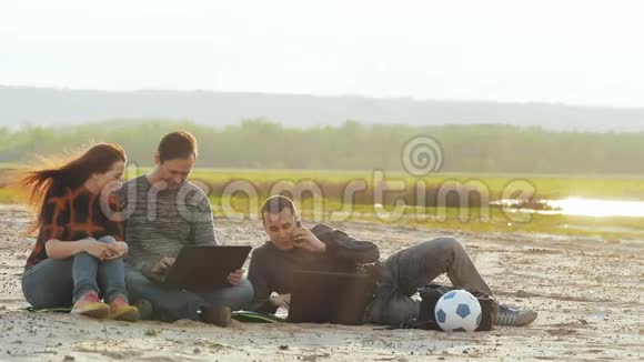 三个人拿着笔记本电脑在沙滩慢动作录像上视频的预览图