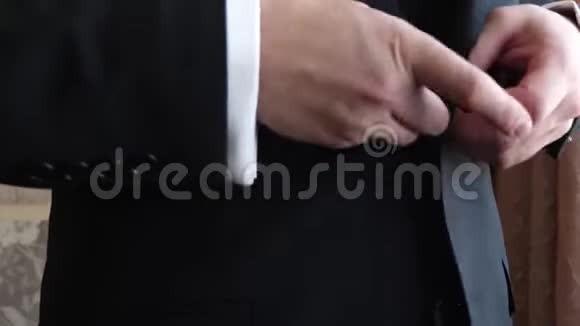 男人在夹克上扣扣子特写视频的预览图