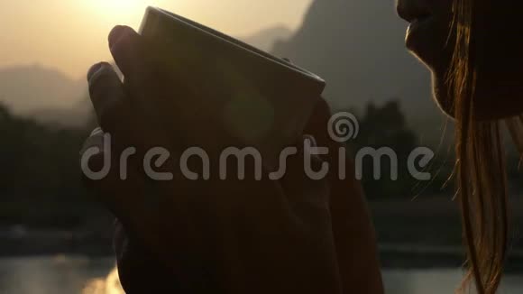 年轻女子在阳台上喝着热咖啡美丽的山景视频的预览图