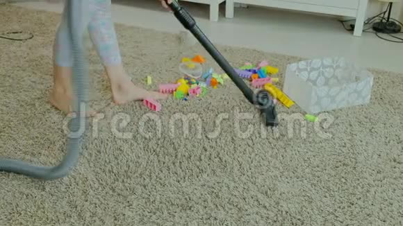 妈妈和女儿一个年轻的女人用吸尘器打扫卫生一个金发的小女孩收集玩具视频的预览图